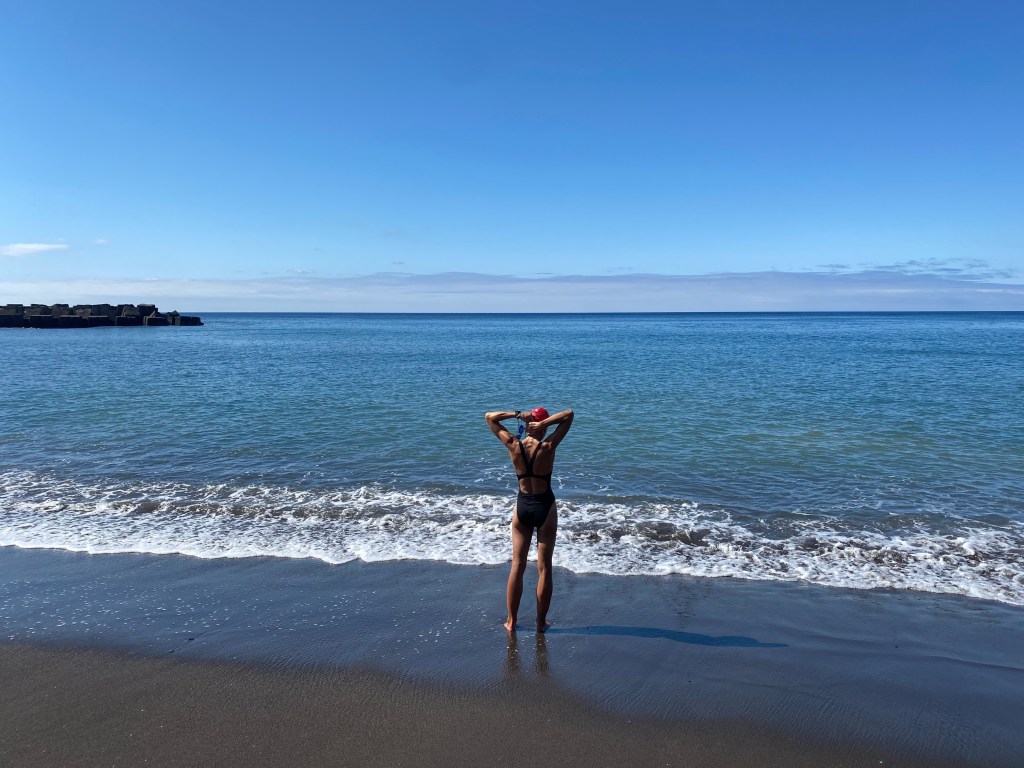 Woman in swimming suit looking out over large bay